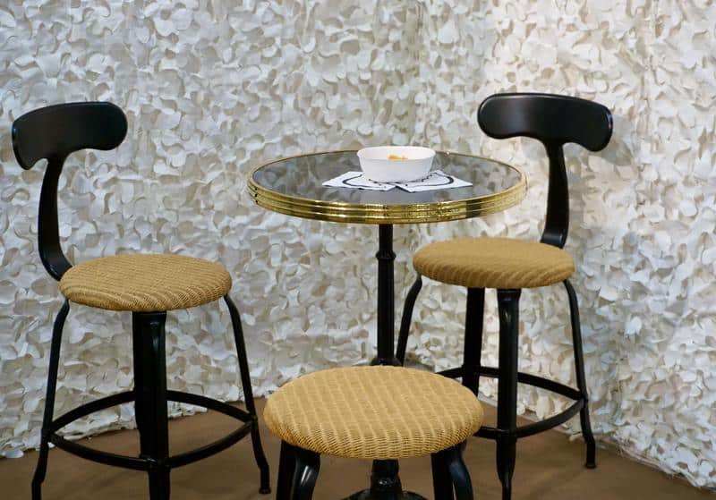 Nicolle metal and loom chair, 45-cm height. Nicolle metal stools and loom chairs in front of an Ardamez table.